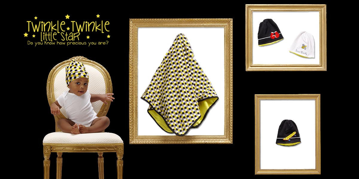 Baby boy wearing an Alli.C beanie hat with silk-lining, and next to baby boy is a matching Alli.C baby blanket with silk-lining, and more Alli.C baby hats with silk-lining.