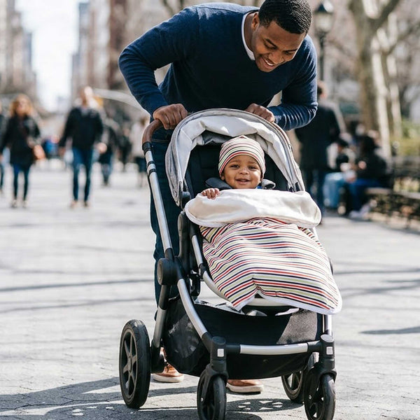Dad pushing a stroller with a baby boy inside wearing Alli.C striped baby gift set with silk lining.